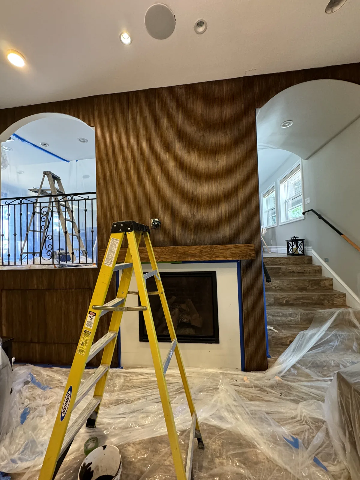 Wood feature wall above a fireplace with a yellow ladder and protected floor