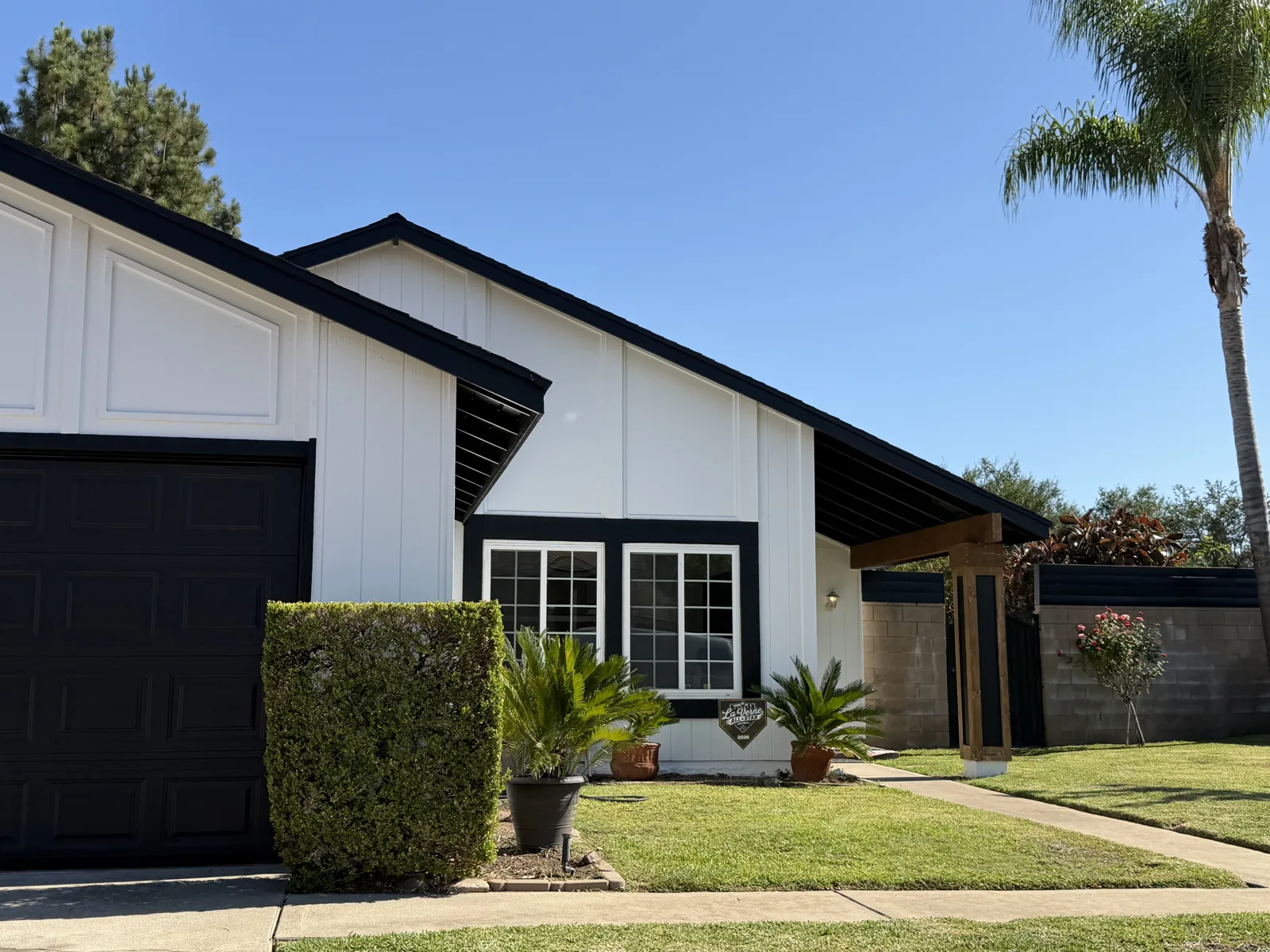 White single-story house with black fascia, window trim, garage door and green lawn