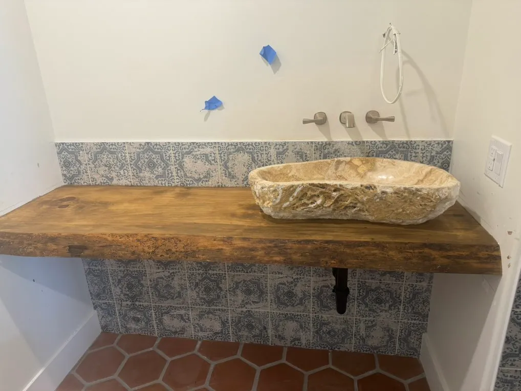 Wood vanity with stone vessel sink and patterned tile backsplash
